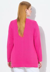 Långärmad rosa tröja med ribbad textur, sidoknittringar och avkopplad passform. Baksidan har en rundad halsringning och slät yta.