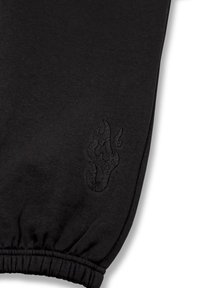 Zwarte katoenen joggers met een elastische tailleband en een gestructureerd zwart vlamlogo nabij de zoom. Zachte stof met een gladde afwerking.