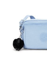 Borsa a tracolla di tessuto blu chiaro con frontale texturizzato, dotata di un portachiavi a forma di gorilla nero e di un accento con logo circolare.