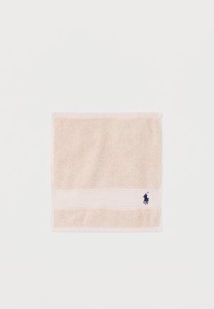 Serviette carrée beige avec tissu texturé et un petit logo brodé d'un joueur de polo bleu marine près d'un coin.