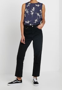 Marinblommig ärmlös topp som matchas med högmidjade svarta jeans och svarta sneakers. Har en mjuk tyg och rak benpassform.