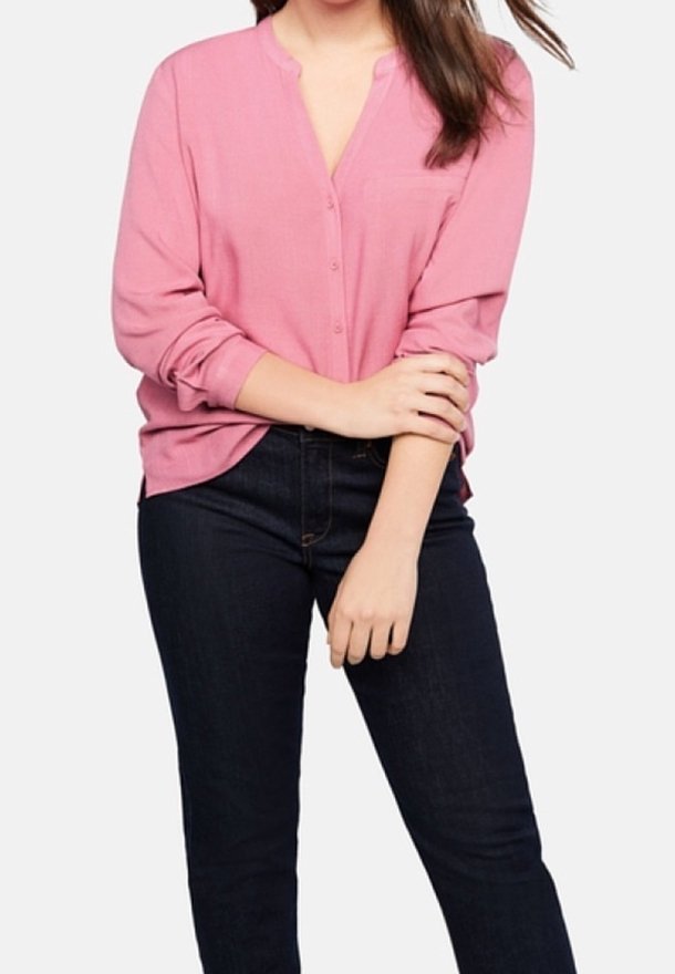 Langærmet, skjortebluse i blød lyserød stof med en afslappet pasform og kravefri design, parret med mørkeblå jeans.