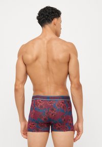 Boxershorts mit einem dunkelroten Blumenmuster auf blauem Hintergrund; elastischer Bund mit blauer Markenkennung; figurbetontes Design.
