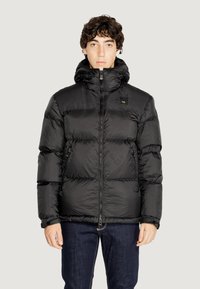 Giubbotto puffa nero con cappuccio, dotato di sezioni trapuntate, zip frontale e tasche laterali. Materiale in nylon liscio con finitura opaca.