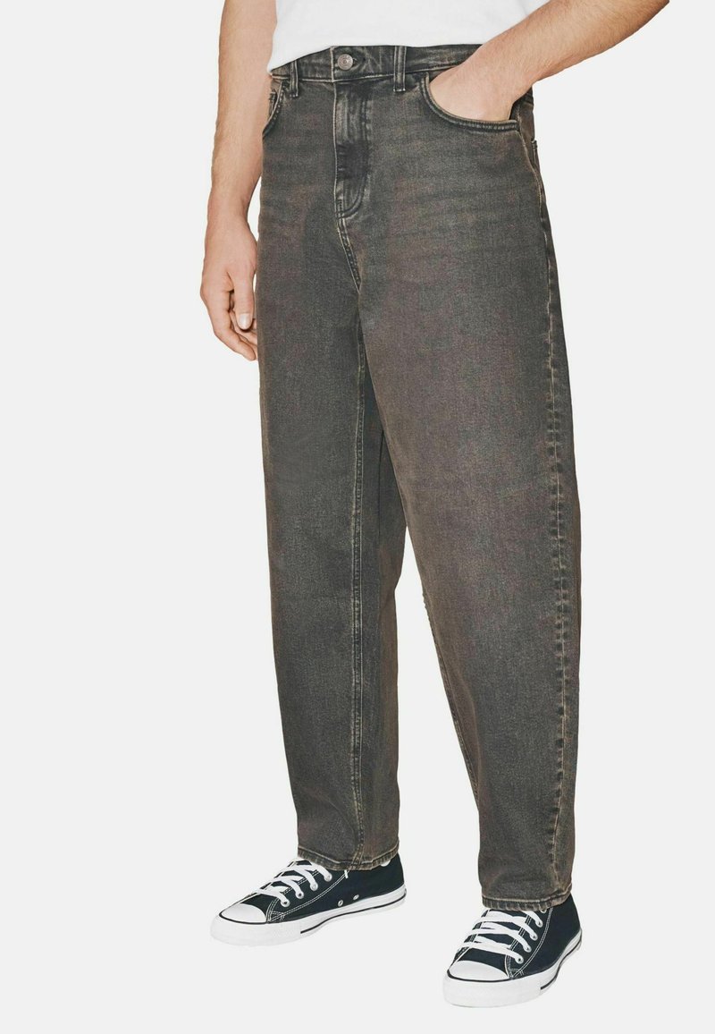 Vaqueros de mezclilla negros de corte holgado, talle alto y diseño de cinco bolsillos, combinados con zapatillas de lona en blanco y negro.