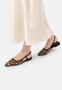 Pantofi slingback cu imprimeu de leopard, cu margini negre și un toc mic. Partea superioară este texturată, având un design cu vârf ascuțit.