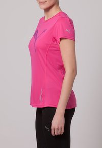 Camiseta deportiva rosa de manga corta, con un diseño gráfico y logo en azul. Fabricada con un tejido ligero que absorbe la humedad.
