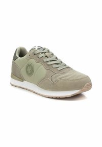Zapatilla deportiva en gris verdoso con paneles de ante y malla, cordones planos, parche con logo y suela blanca. Cuenta con una puntera redondeada y acentos de goma.