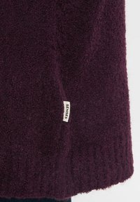 Dunkellila Pullover aus strukturiertem Stoff. Verfügt über einen gerippten Saum und ein kleines "SENSES"-Label an der Seite. Weicher und plüschiger Look.