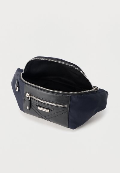 Τσαντάκι μέσης από ύφασμα σε μπλε ναυτικό και μαύρο χρώμα με ανοιχτό κύριο φερμουάρ και μπροστινή τσέπη με φερμουάρ και μεταλλική ετικέτα με το εμπορικό σήμα.