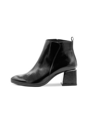 Černá kožená kotníková bota s hladkým povrchem, špičatou špičkou a robustním čtvercovým podpatkem. Má poutko na zadní straně pro snadné obouvání.