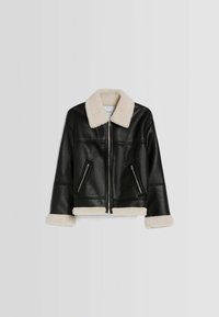 Svart fusk läderjacka med vit sherpa-foder på kragen, ärmarna och nederkanten. Jackan har framfickor med dragkedja och snedställda fickor.