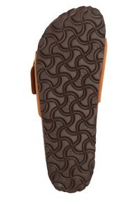 Brown rubber outsole featuring a wave pattern for grip, with a tan suede upper and adjustable strap on the side.