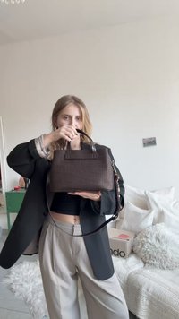 Bruine synthetische handtas met een textuurrijke weving, dubbele handvatten aan de bovenkant en een afneembare schouderriem. Compacte, rechthoekige vorm.