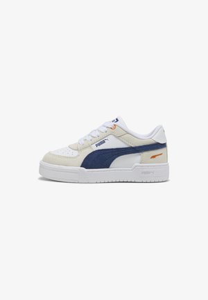 Baskets Puma blanches et beiges avec une bande en daim bleu marine, détail orange près du talon, lacets blancs et semelle texturée sur un fond blanc.
