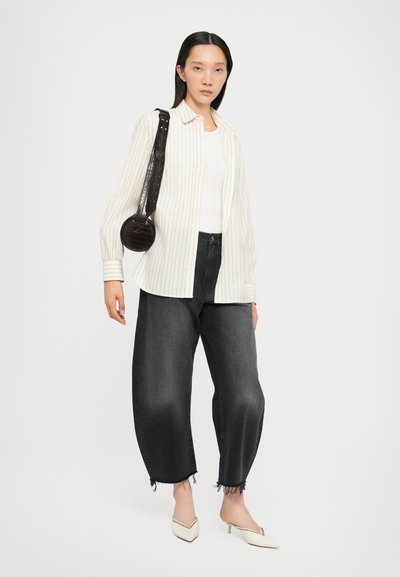 White striped button-up shirt, fitted white tank, dark high-waisted jeans with frayed hem, and cream-colored pointed heels; round black bag.