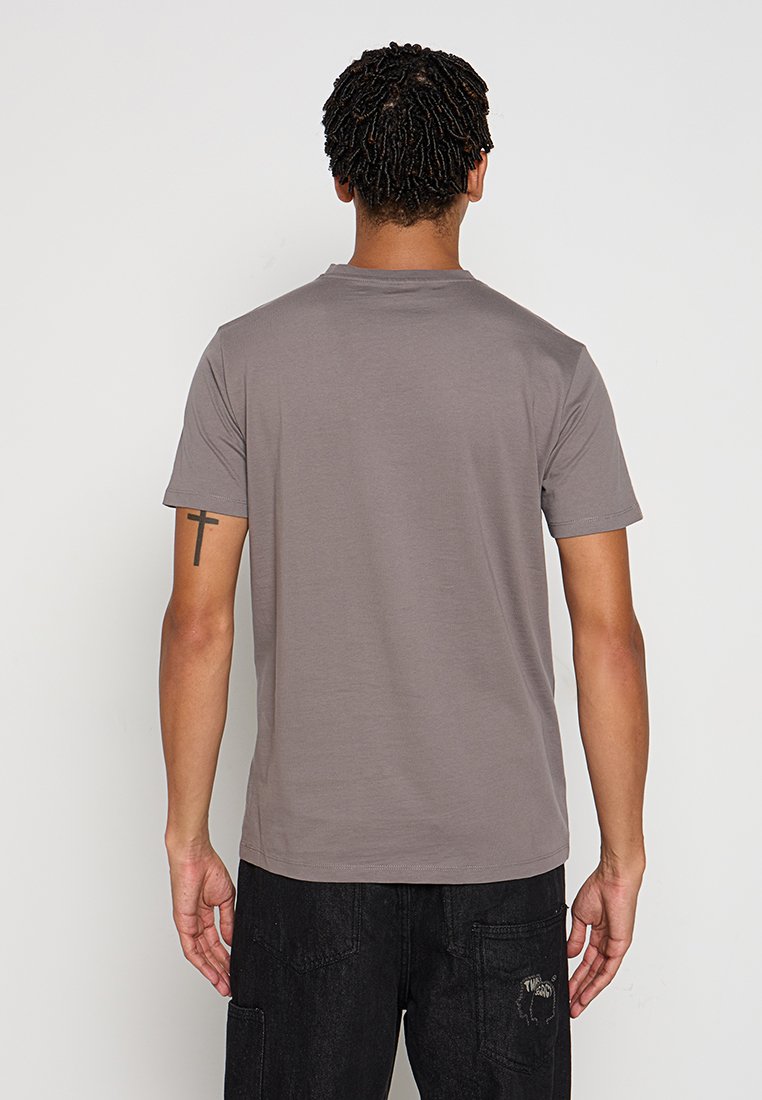 Graues Baumwoll-T-Shirt mit kurzen Ärmeln, rundem Ausschnitt und minimalistischer Gestaltung. Getragen mit dunklen Hosen, zeigt eine schlichte Rückansicht.