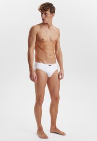 Witte katoenen slip, snug fit, klassiek ontwerp, elastische tailleband met een klein logo, gladde textuur en minimalistische stijl.