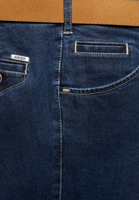 Jean en denim bleu foncé à la texture lisse, avec un logo MEYER argenté, des coutures dorées et une ceinture en cuir beige.