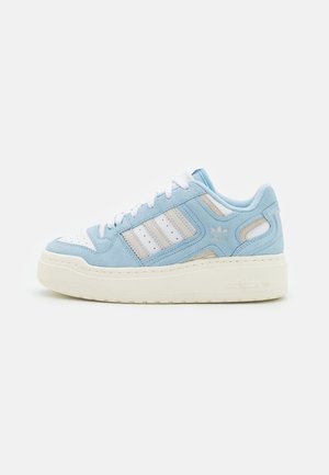 Niskie sneakersy Adidas w jasnoniebieskim zamszu i białej skórze, z białymi sznurowadłami, trzema paskami i grubą beżową podeszwą.