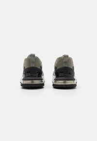 Nike sneakers with a green upper, black accents, and transparent air cushioning sole. Features textured fabric and a rear loop for easy wear.