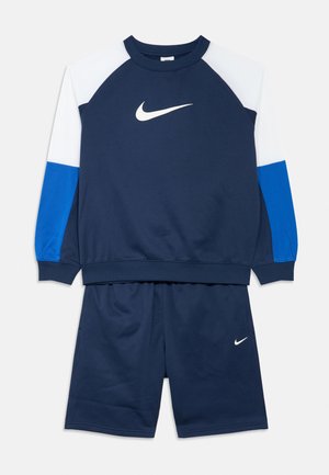 Granatowa bluza Nike z białymi i niebieskimi rękawami w stylu color-block, zestawiona z dopasowanymi granatowymi szortami z małym białym logo Nike.