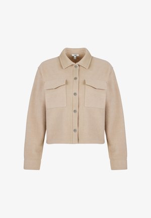 Beige kurz geschnittene Jacke aus weichem Stoff, mit Hemdkragen, zwei vorderen Taschen und silbernen Druckknöpfen. Glatte Textur.