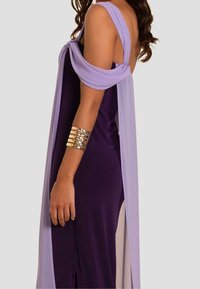 Lila Jerseykleid mit lilafarbenem Überwurf, der über die Schulter drapiert ist. Es hat einen Oberschenkel hohen Schlitz und ein goldenes Armreif.