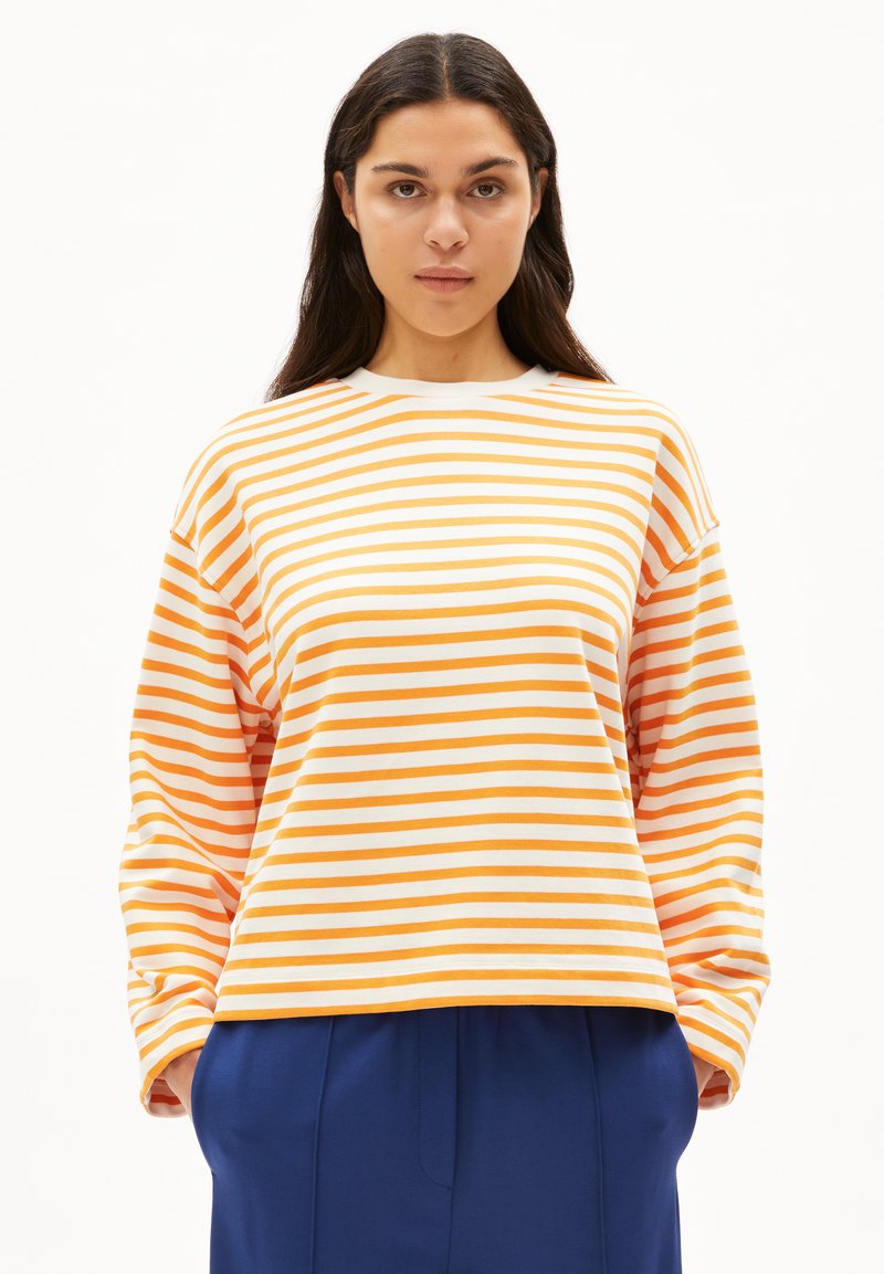 T-shirt a righe a maniche lunghe in bianco, arancione e giallo. Vestibilità ampia, scollatura rotonda e spalle scese, abbinata a pantaloni blu.