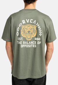 Olijfgroen katoenen T-shirt met een grote afbeelding van een tijger omringd door tekst, met een ontspannen pasvorm en korte mouwen.