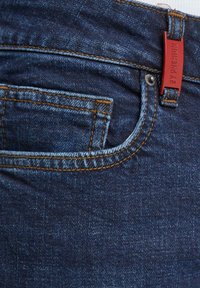 Vaqueros de denim en azul oscuro con costuras en azul claro, un bolsillo frontal y una etiqueta roja en la cinturilla marcada como "2Y PREMIUM."