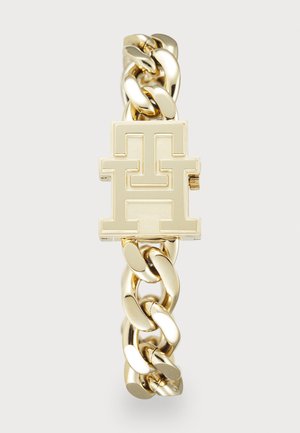 Bracelet en chaîne dorée avec un grand fermoir rectangulaire poli présentant un design de logo entrelacé "TH" en relief.
