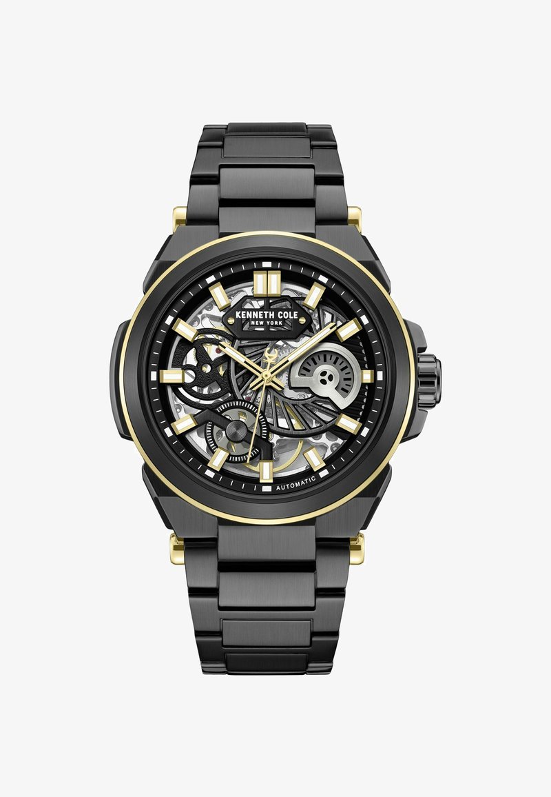 Czarny zegarek ze stali nierdzewnej z czarną i złotą szkieletową tarczą, z luminescencyjnymi znacznikami godzin i czarnym bransoletą ogniwową. Widoczny automatyczny mechanizm.