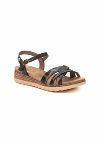 Sandali in pelle marrone con cinturini incrociati, dettagli in stampa leopardo, una cinturino alla caviglia regolabile e una suola piatta di un beige chiaro.