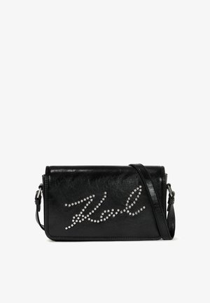 Sac bandoulière en cuir noir avec script "Karl" clouté en argent sur le devant et bandoulière réglable.