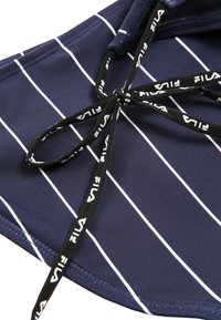 Tkanina w granatowe paski z białymi liniami, z czarnym sznurkiem ściągającym z logo Fila. Gładka tekstura, przeznaczona do sportu lub codziennego noszenia.
