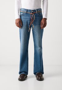 Blaue Denim-Jeans mit lockerem Schnitt, ausgestattet mit einem Kordelzugbund in Braun und Rot. Glatte Textur und weite Beine.