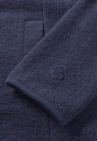 Marineblauwe gevilte wollen trui met mouwen, voorzien van een geribde manchet en een subtiele geborduurde logo. Glad textuur, strakke lijnen en een minimalistisch ontwerp.