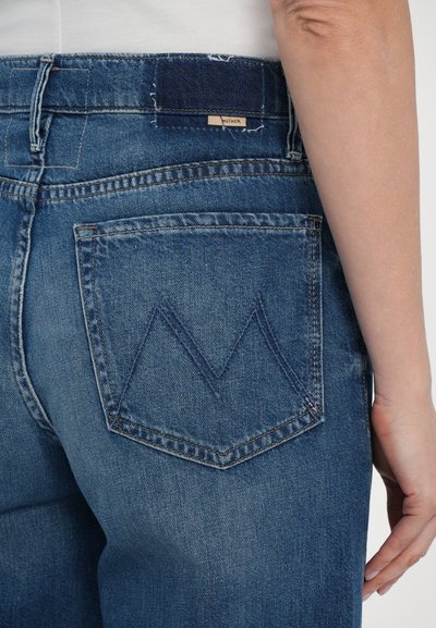 Blue denim jeans featuring a high waist, five-pocket design, and distinctive V-shaped stitching on the back pockets. Soft texture.