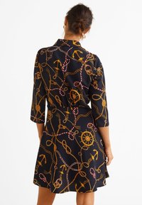 Abito navy con maniche a tre quarti, caratterizzato da un motivo di ancore e corde dorate. Taglio a trapezio con orlo svasato. Tessuto liscio e leggero.