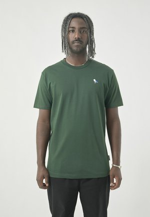 Grünes T-Shirt mit kurzen Ärmeln aus weichem Material, das ein kleines blaues Vogel-Logo auf der Brust zeigt; Rundhalsausschnitt und lockere Passform.