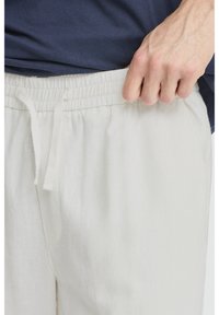 Světle béžové teplákové kalhoty z měkké, strukturované tkaniny s elastickým pasem a nastavitelným šňůrkou.