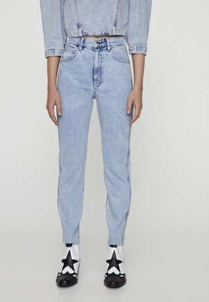 Lyseblå jeans med højtaljet pasform, brugt sammen med cropped denimjakke og hvide ankelstøvler med store sorte stjerner foran.