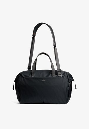 Sac polochon noir en tissu texturé. Comprend deux poignées, une sangle ajustable et un logo discret sur le devant. Design élégant et fonctionnel.