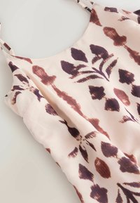 Ärmelloses Kleid mit Blumenmuster aus weichem pfirsichfarbenem Stoff mit tief bordeauxroten Akzenten, das eine zarte Textur und verstellbare Träger aufweist.