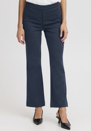 Tumši zili pieguļoši bikses ar taisnu kāju dizainu, platu josta vietu un gludu tekstūru. Kopā ar melniem, smailiem papēžiem.