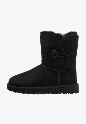 Botte d'hiver noire en suède mi-mollet avec fermeture par bouton et boucle, doublure en shearling moelleux et semelle en caoutchouc texturée pour une bonne adhérence.
