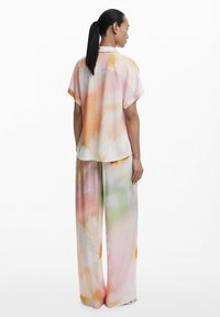 Ľahká blúzka s krátkym rukávom a široké nohavice v pastelových farbách s kvetinovým vzorom. Hladká tkanina s jemnou textúrou.