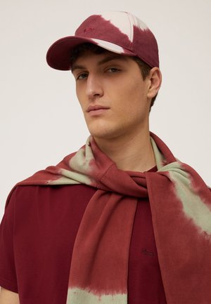 Maroon cap with white tie-dye pattern, paired with a maroon shirt and a green-accented scarf draped around the shoulders.