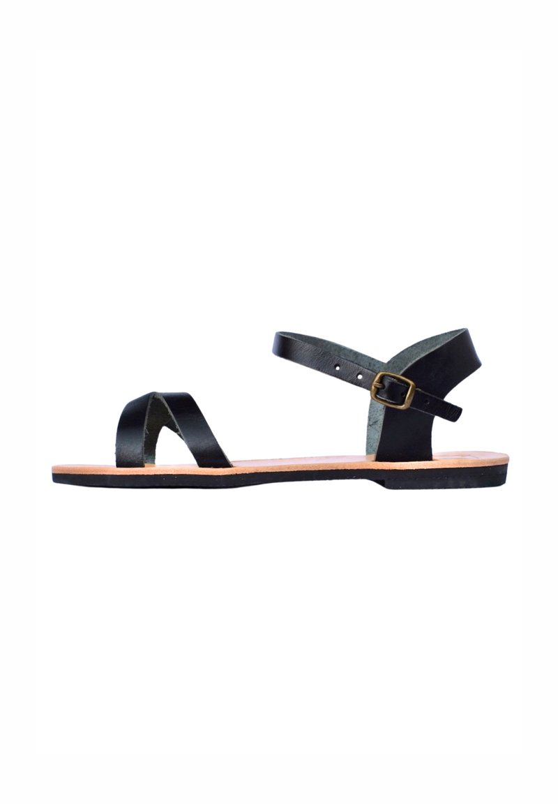 Zwarte leren sandalen met twee gekruiste banden, een verstelbare enkelband met gesp en een platte bruine zool.